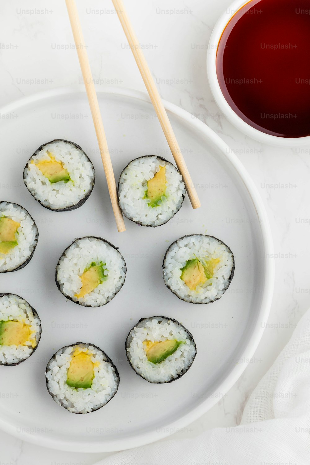 ein weißer Teller mit Sushi und Essstäbchen
