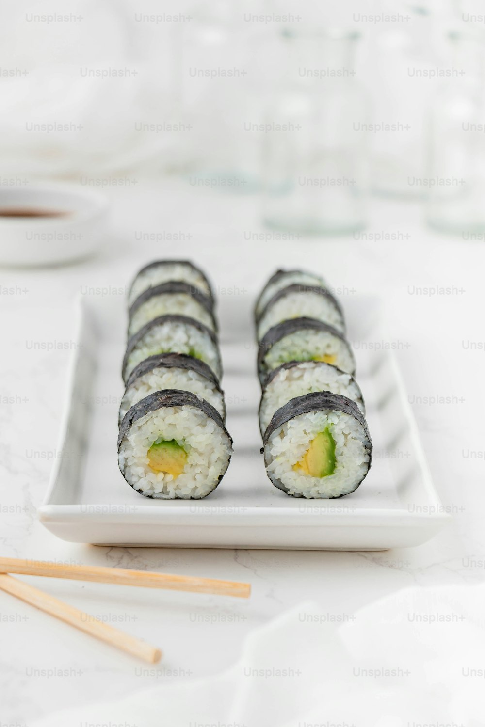 Un plato blanco cubierto con sushi y palillos