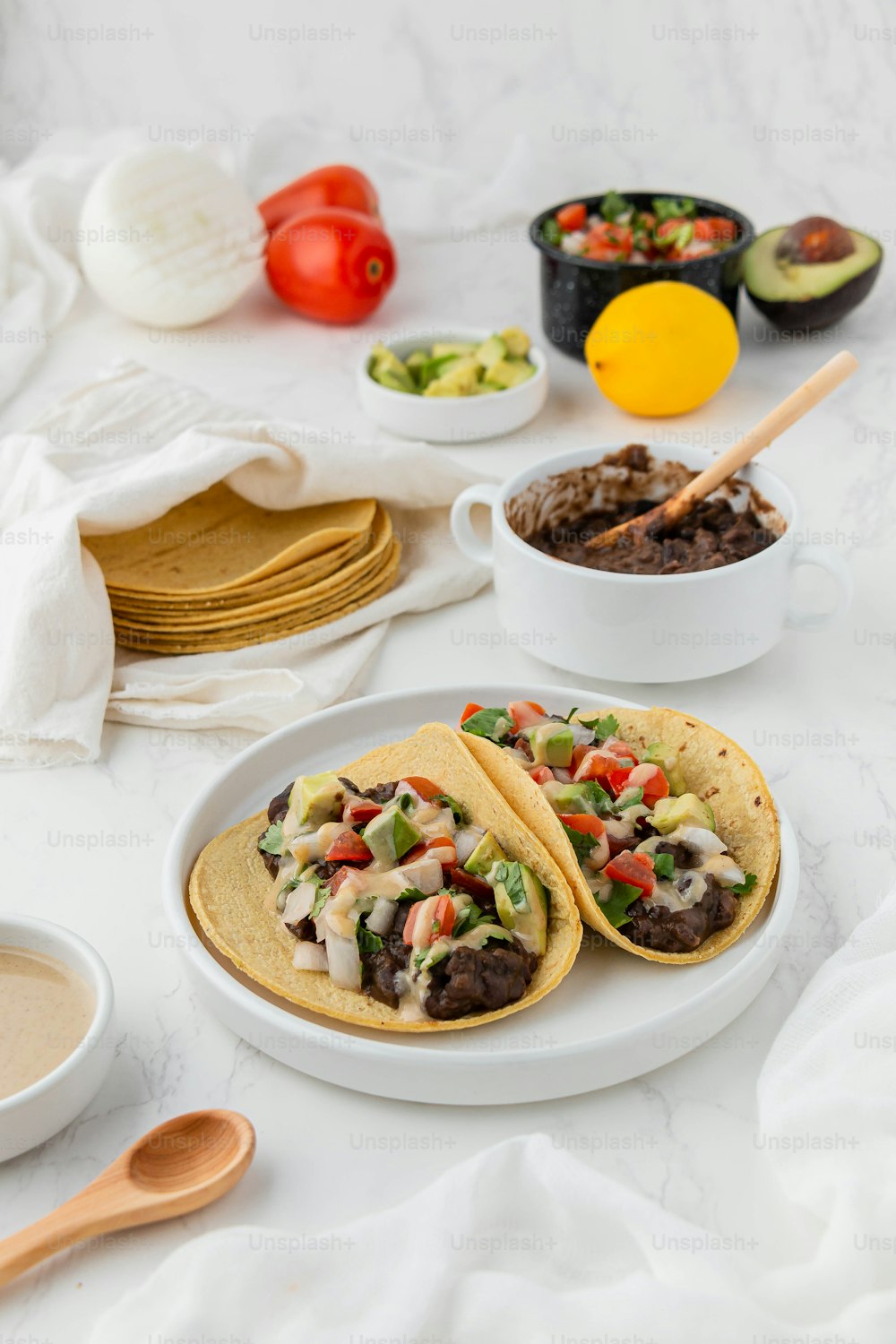 a white table topped with tacos and bowls of food