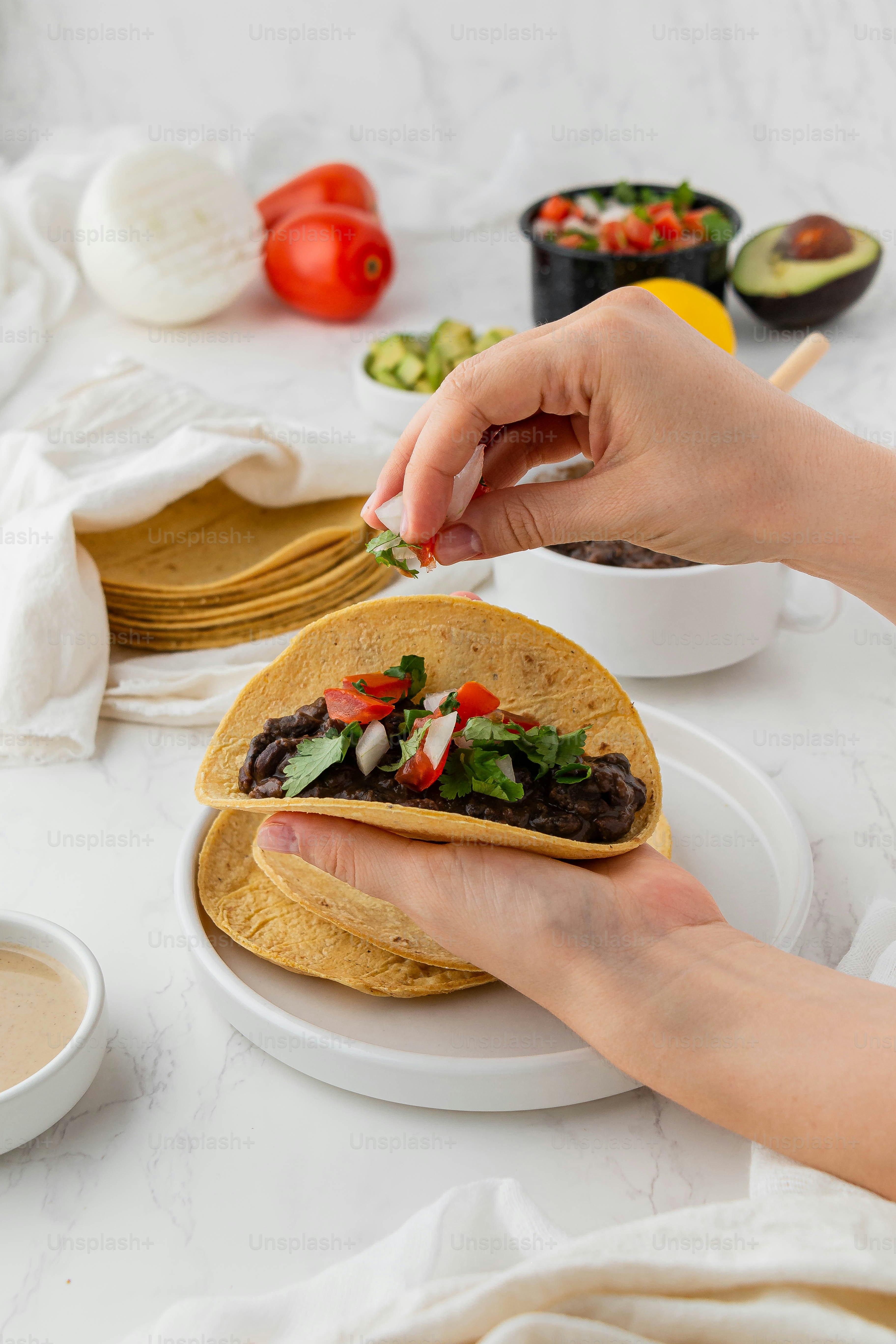 a person holding a tortilla on a white plate