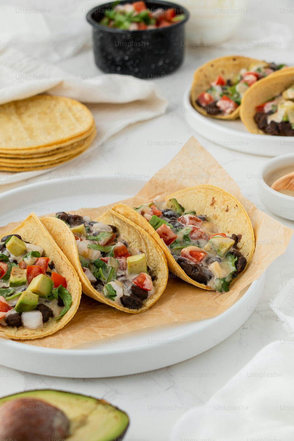 une assiette blanche surmontée de trois tacos à côté d’un bol de salsa