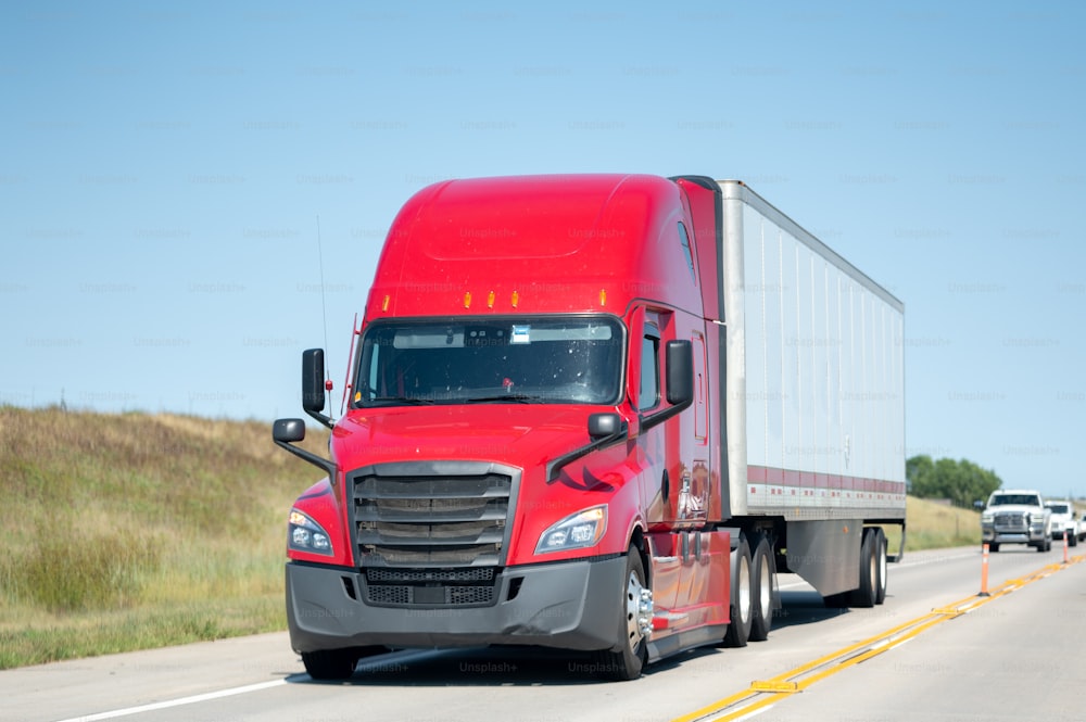 a red semi truck driving down a highway