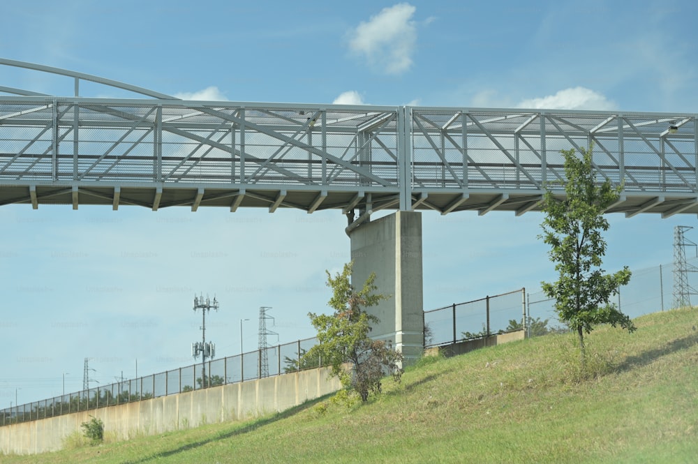 a bridge over a grassy hill with a sky background