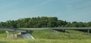 a highway bridge over a grassy field with trees in the background