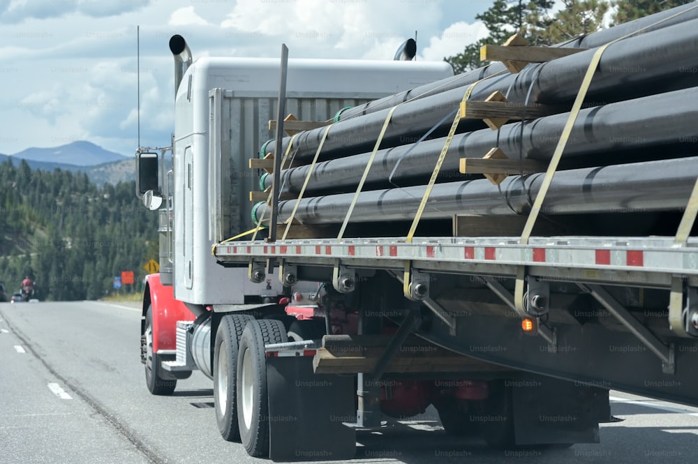 a semi truck with a load of pipes on the back of it