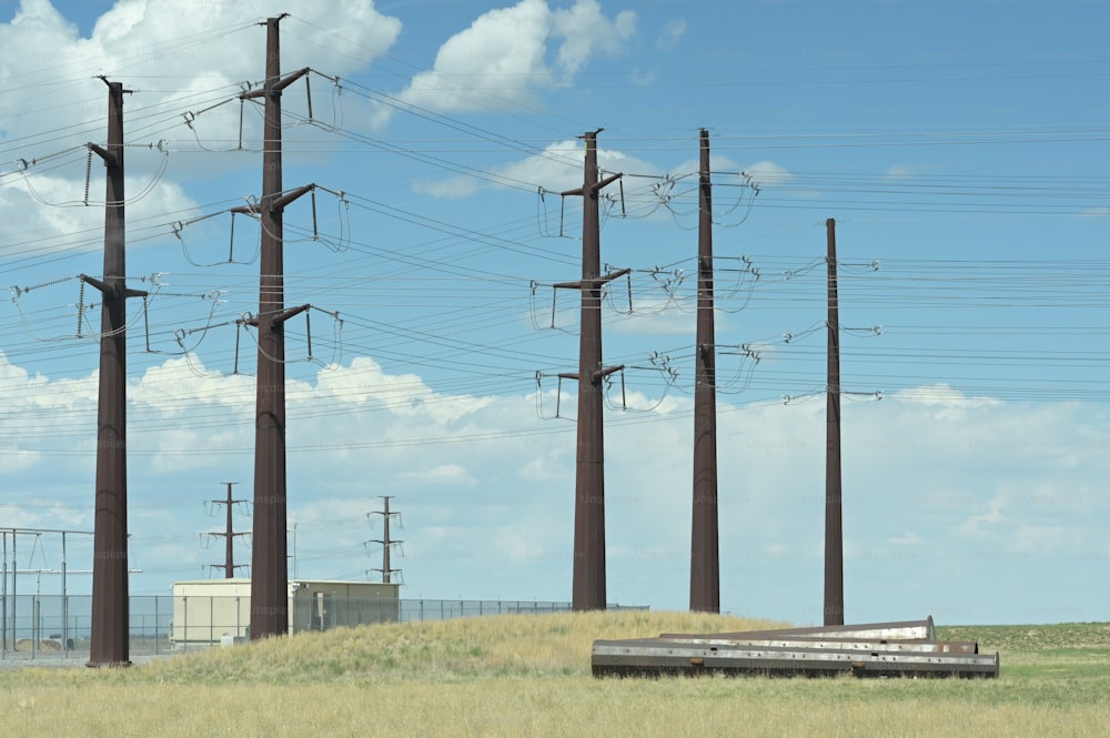a grassy field with telephone poles and a train on the tracks