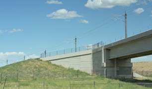 eine Brücke über einen grasbewachsenen Hügel mit Stromleitungen darüber