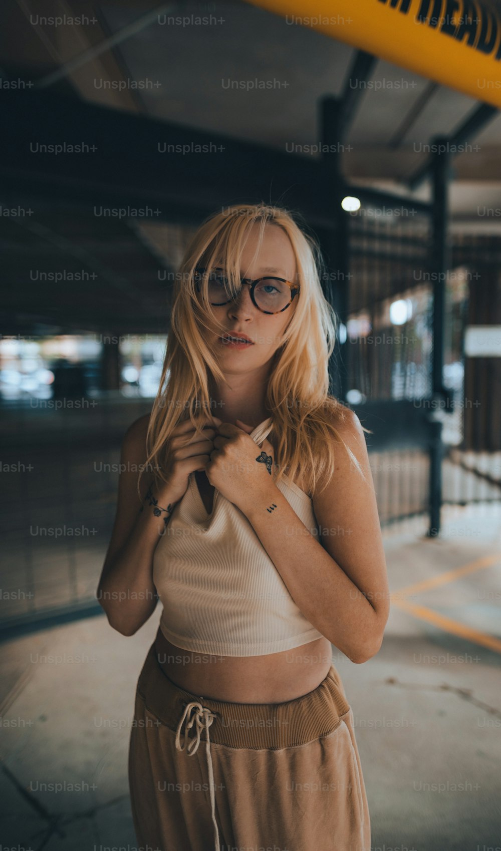 a woman wearing glasses standing in a parking garage