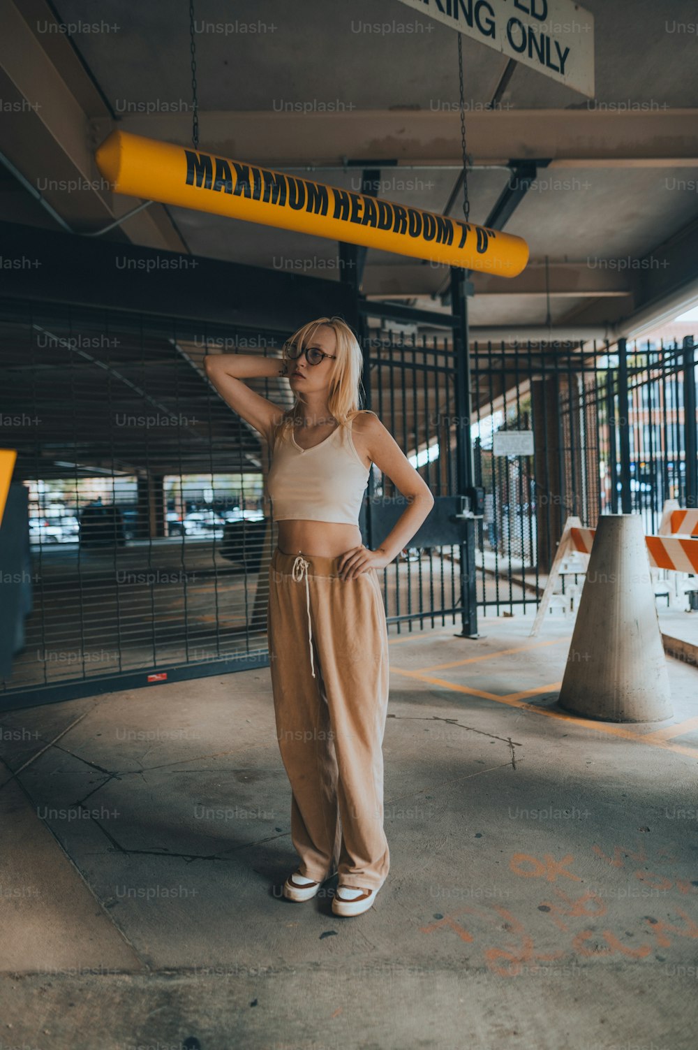 a woman standing under a yellow sign in a parking garage