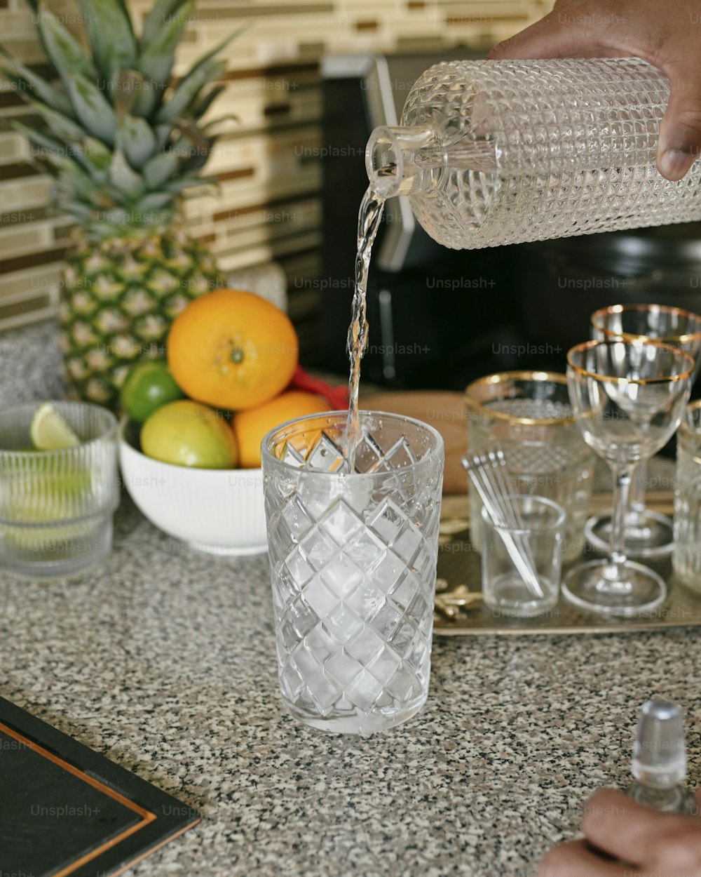 a person pouring water into a glass on a counter