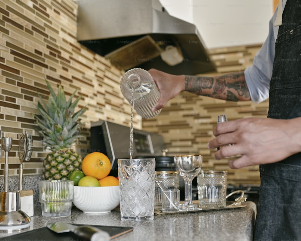 um homem despejando água em um copo em uma cozinha