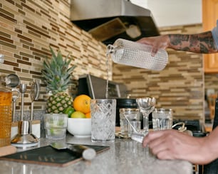 a man pouring water into a glass in a kitchen