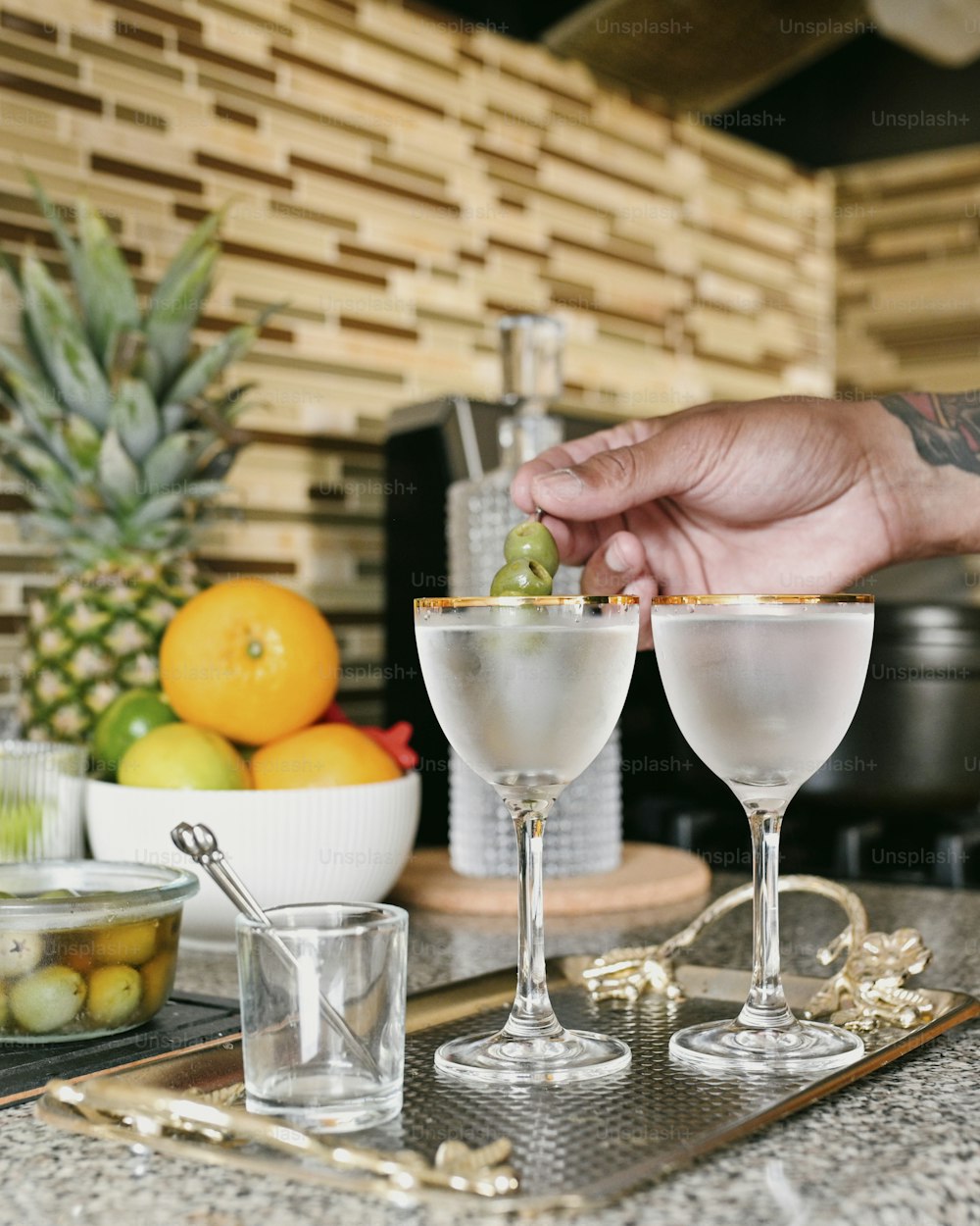 a person is putting a piece of fruit in a martini glass