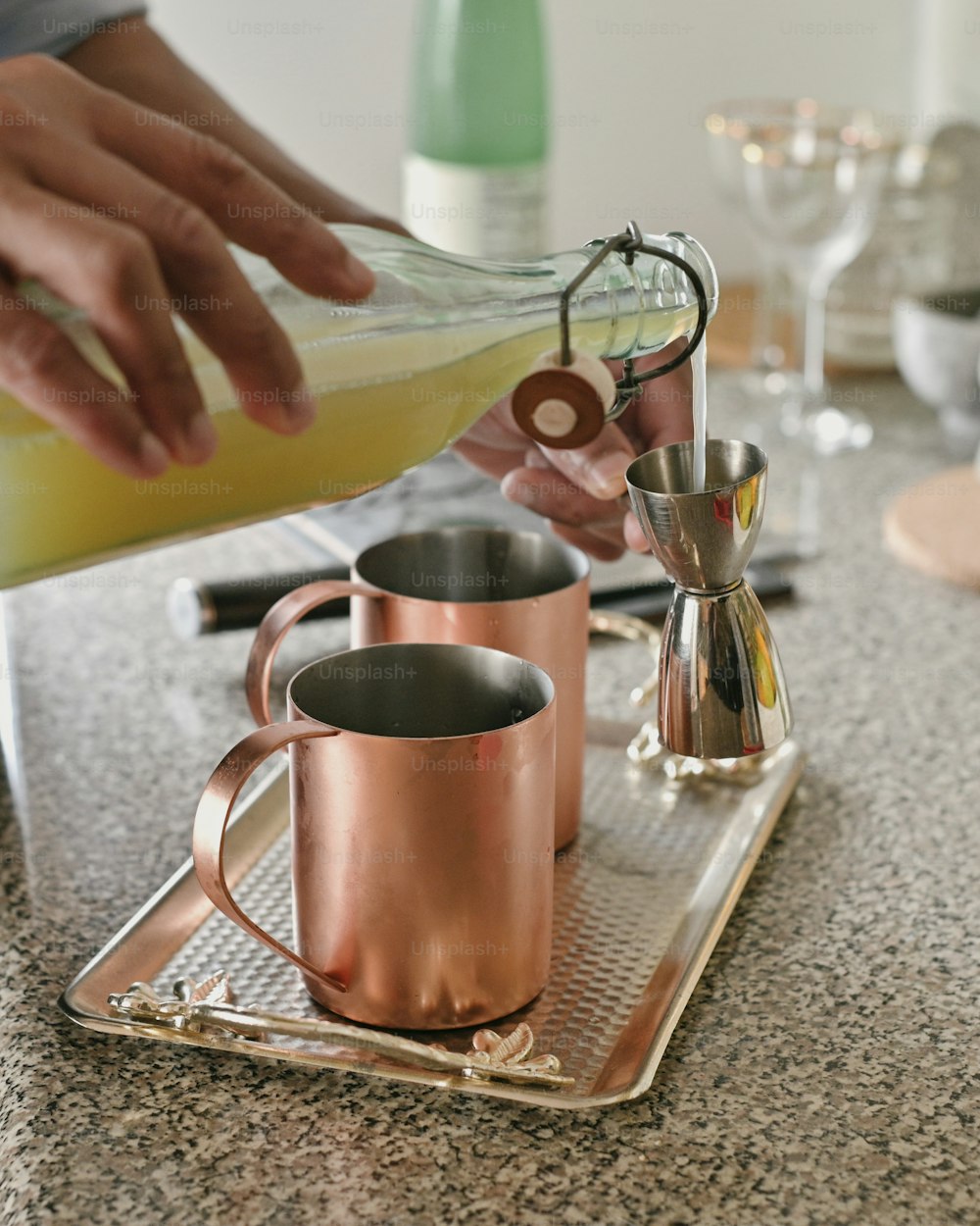 a person pouring a drink into a copper mug