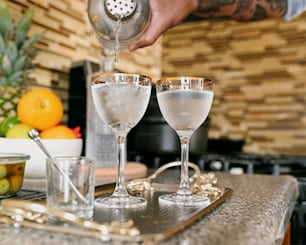 a person pouring a drink into two glasses