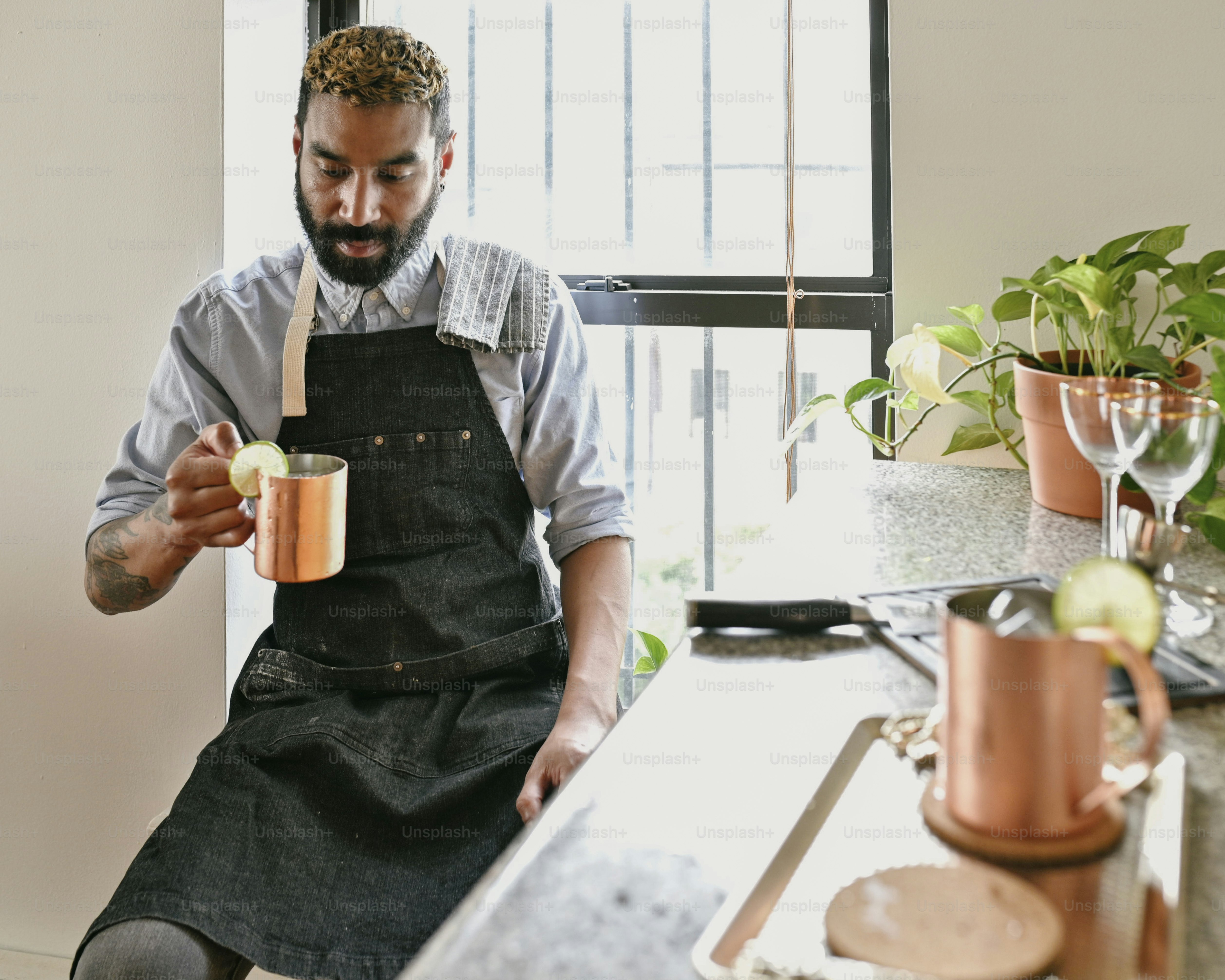 a man in an apron is holding a mug