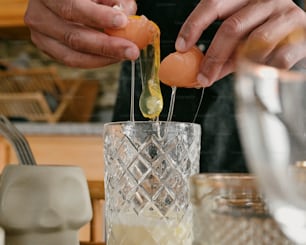 a person is putting an egg in a glass