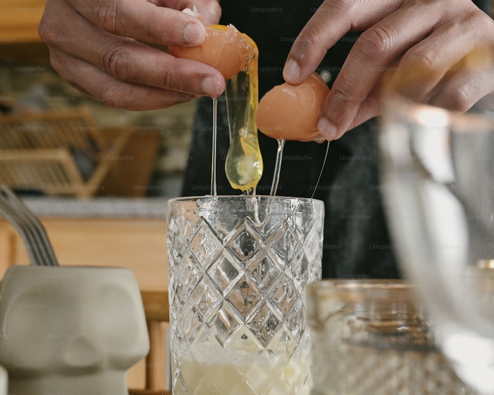 a person is putting an egg in a glass