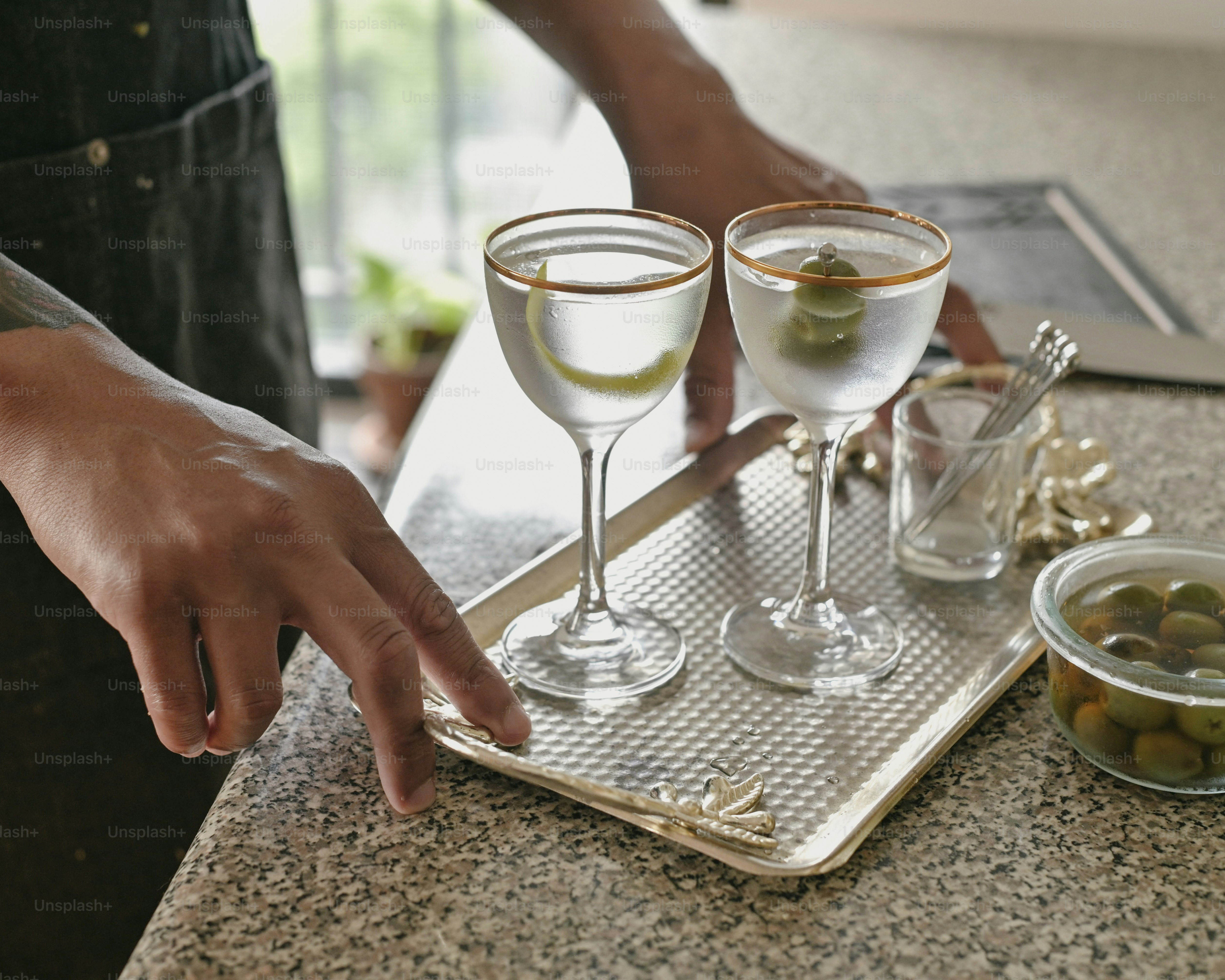 a tray with two glasses of wine and a bowl of olives