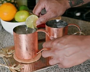 a person is putting a lime in a copper mug