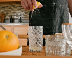 a person in a kitchen squeezing a lemon into a glass