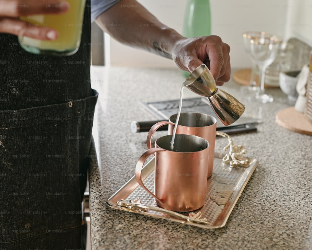 a person pouring a drink into a copper mug