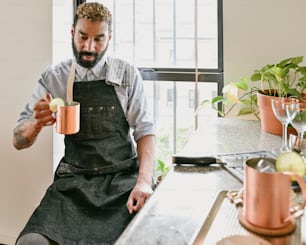 a man in an apron is holding a cup