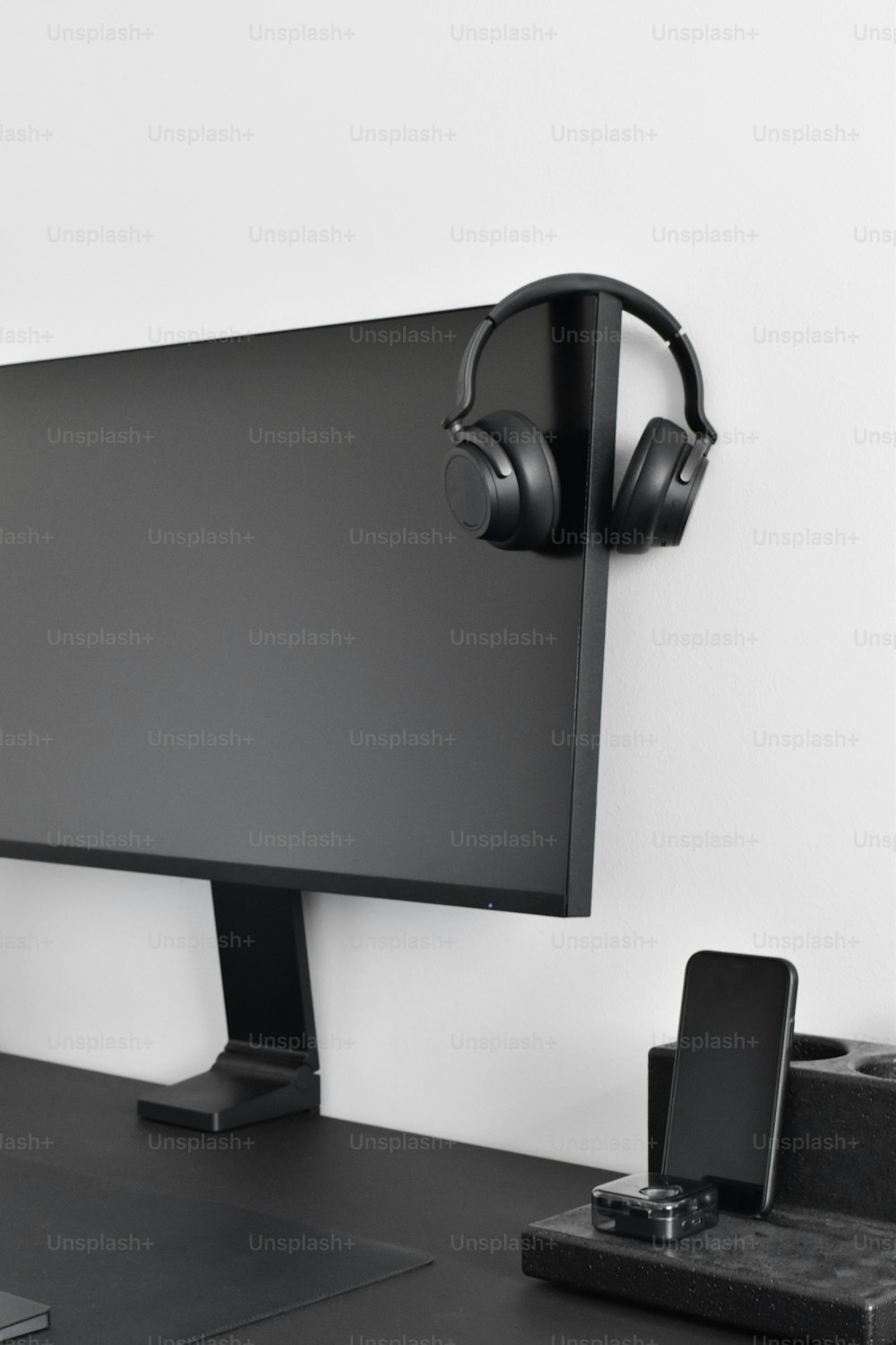 um monitor de computador com fones de ouvido em uma mesa