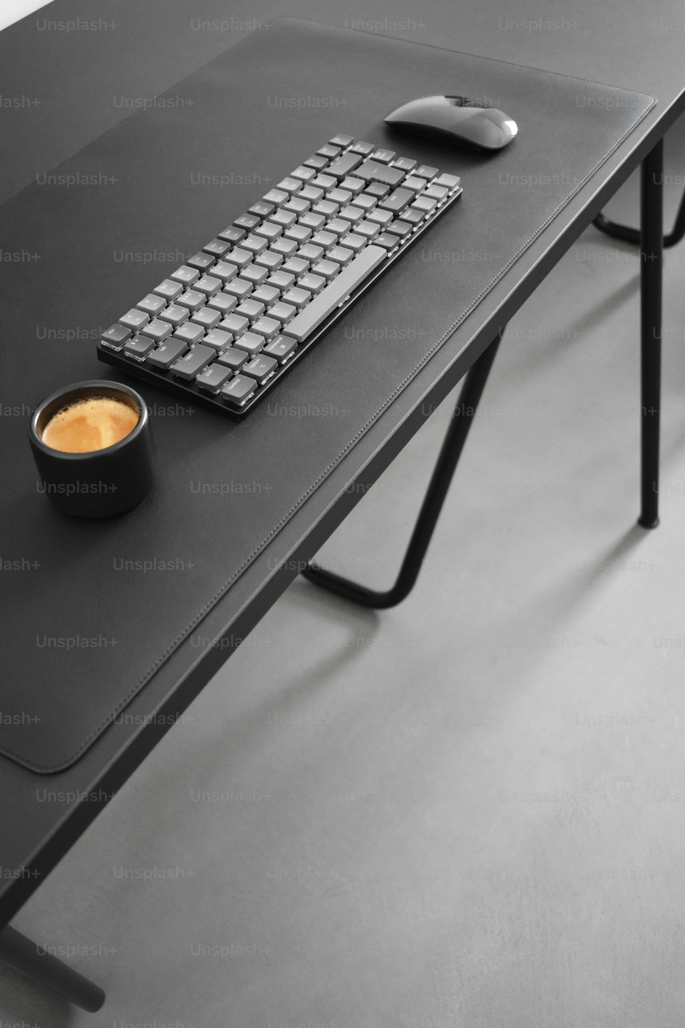 a computer desk with a keyboard, mouse and cup of coffee