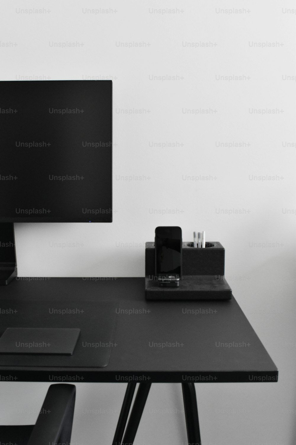 ein Schreibtisch mit einem Computermonitor und einem Handy darauf