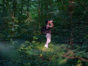 Una mujer está tomando una foto en el bosque