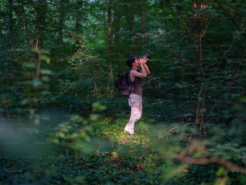 a woman is taking a picture in the woods