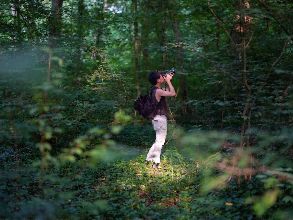Una mujer está parada en el bosque con una cámara