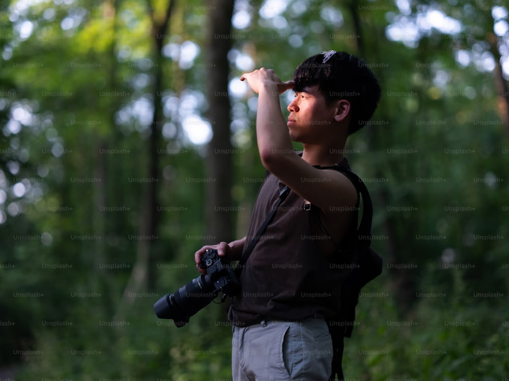 a man holding a camera and taking a picture in the woods