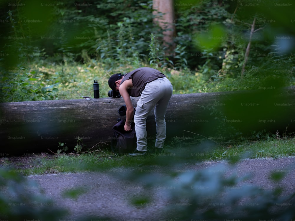 a person leaning over a log in the grass