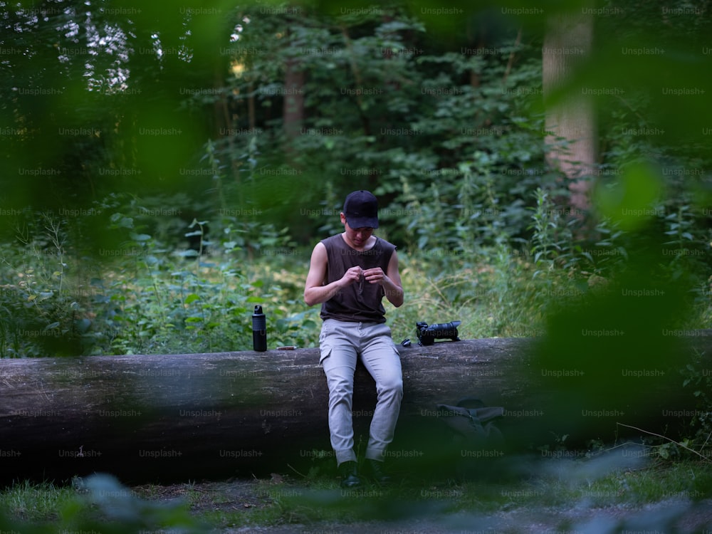a man sitting on a log looking at his cell phone