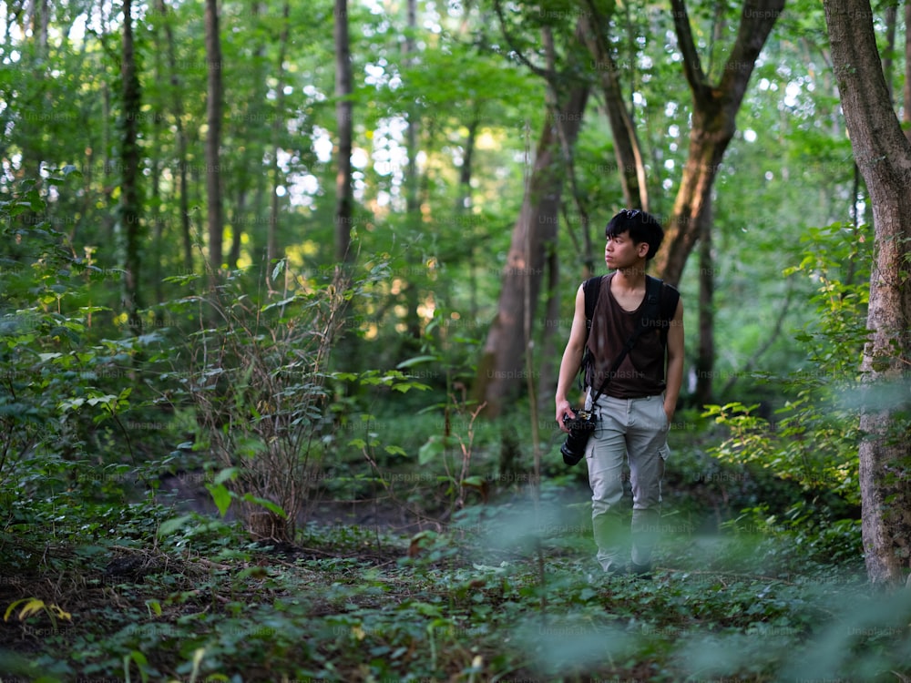 a man is walking through the woods with a camera