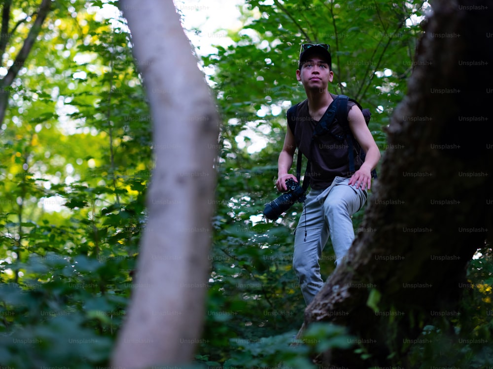 um homem parado na floresta com uma câmera