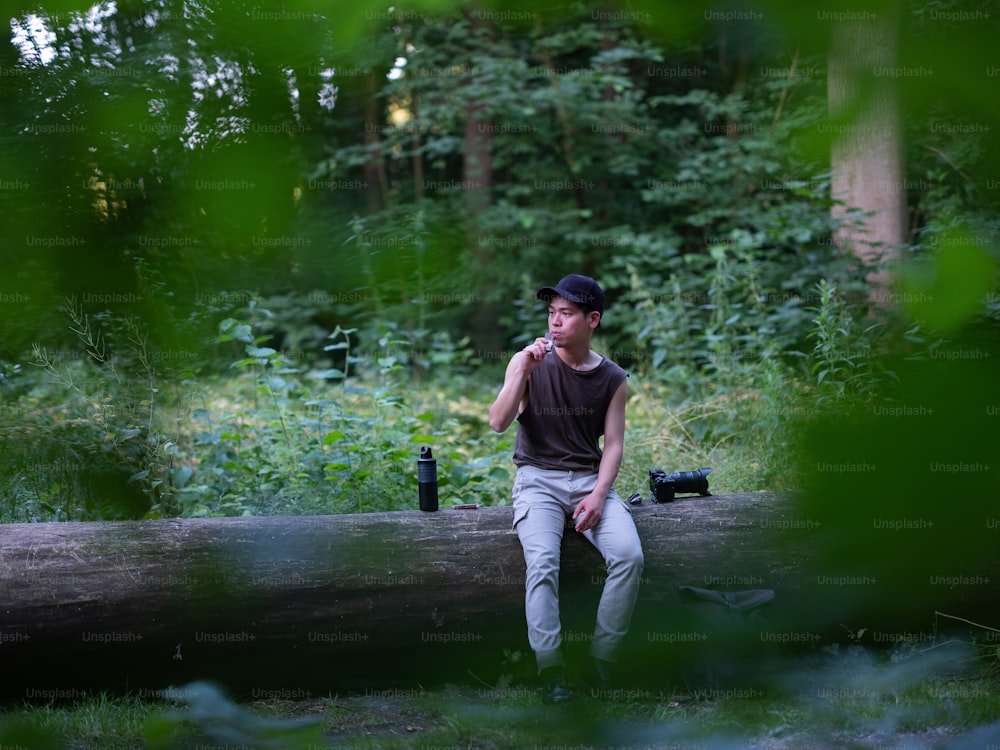 Un hombre sentado en un tronco en el bosque
