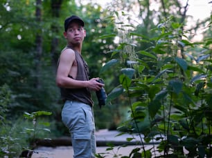 a man standing in the woods holding a camera