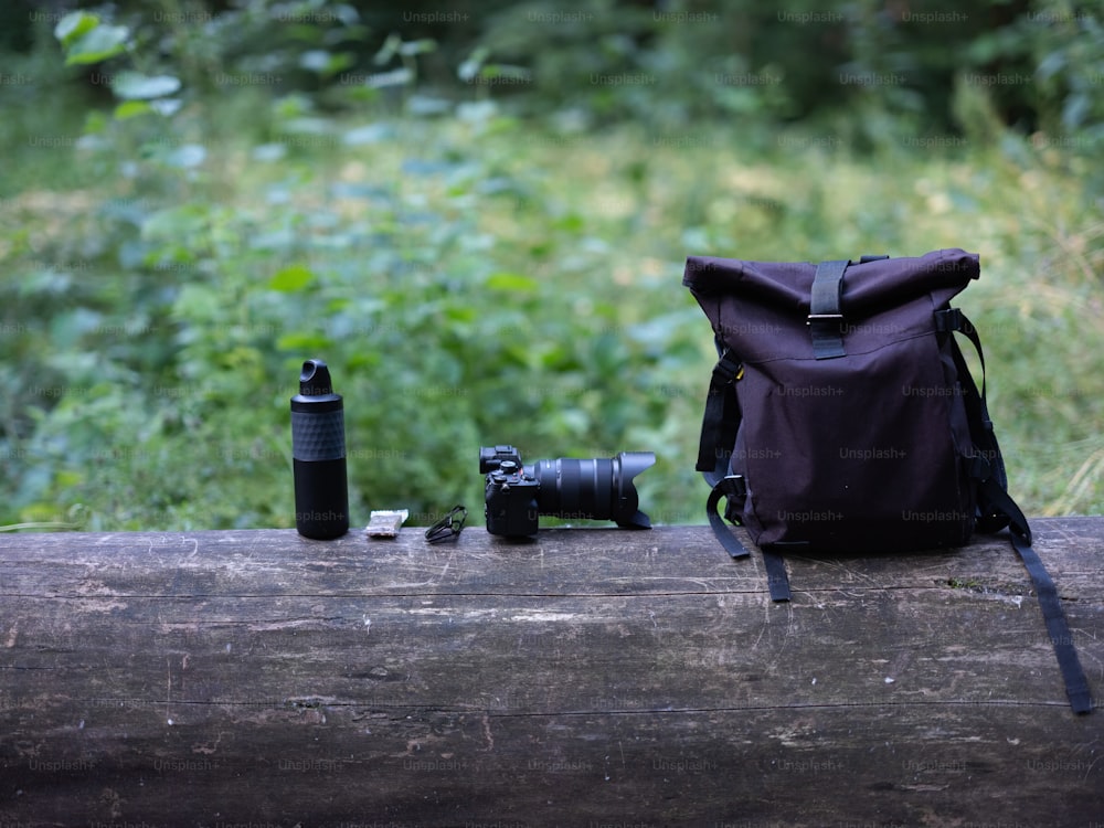 a camera and a backpack sitting on a log