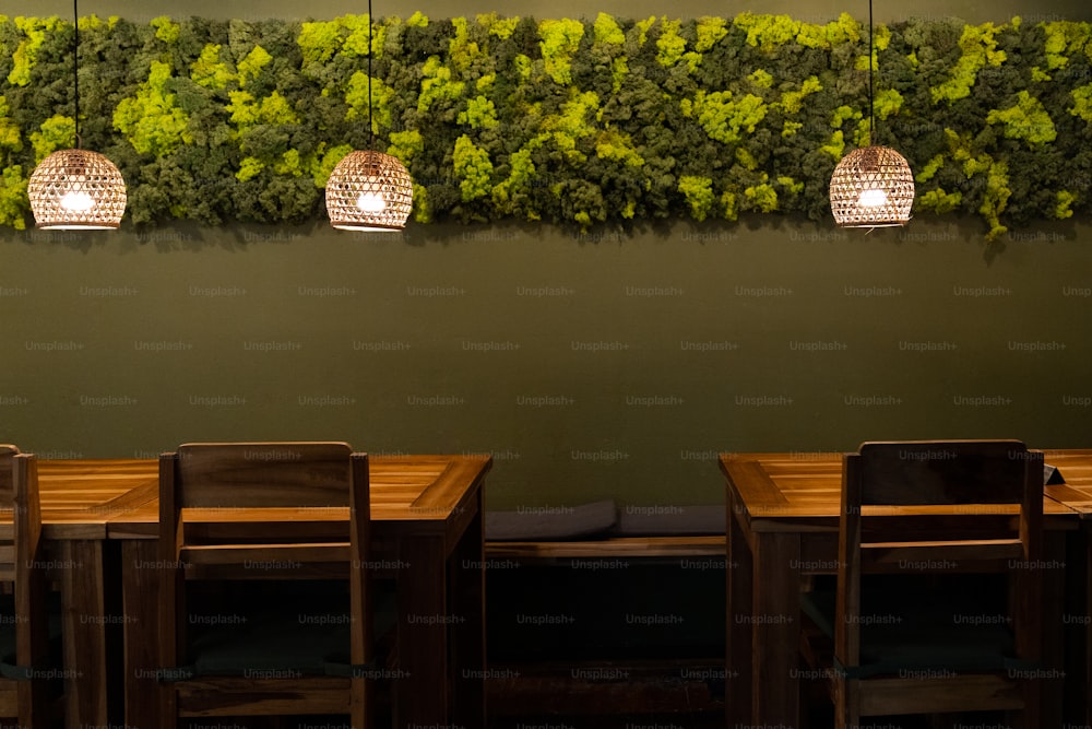 a green wall with three hanging lights above a wooden table