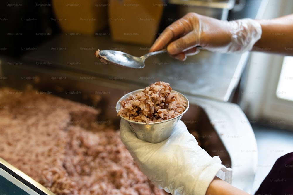 uma pessoa segurando uma colher sobre uma tigela de comida