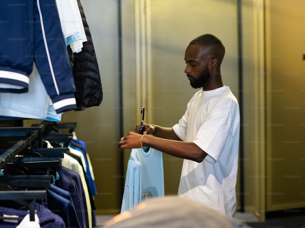um homem parado em frente a um rack de camisas