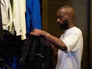 a man holding a jacket in front of a rack of clothes