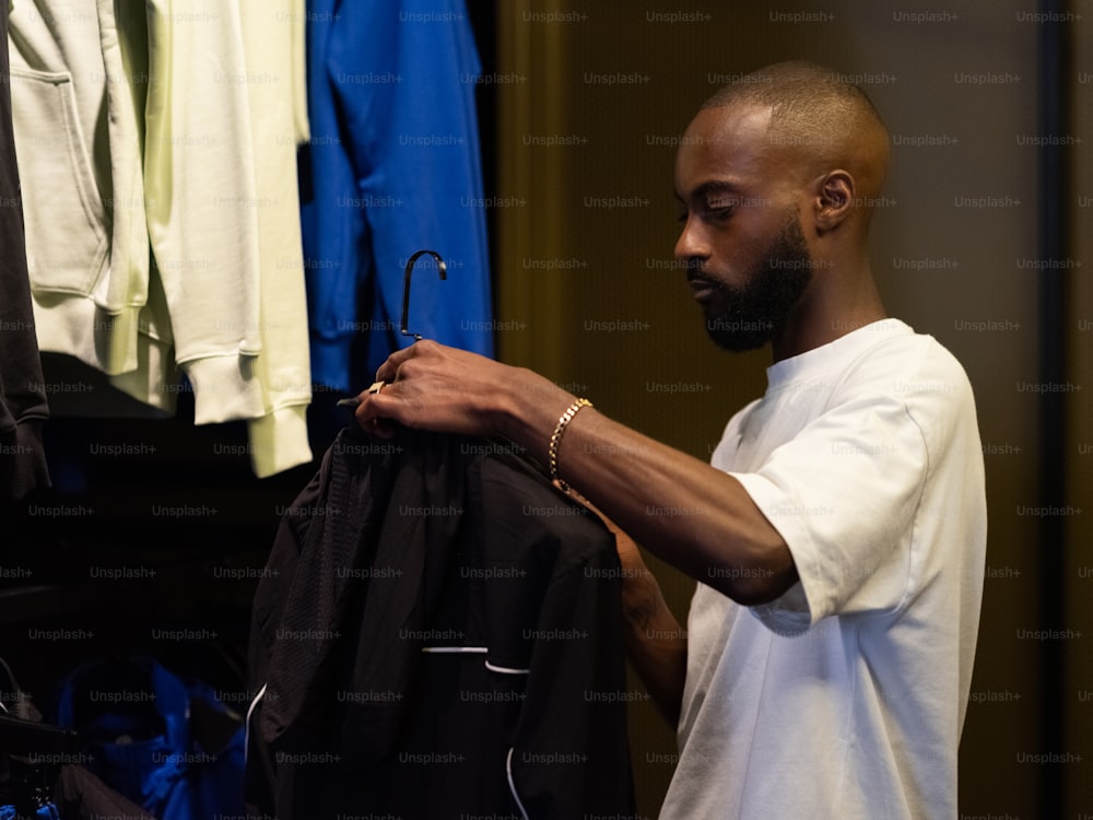 um homem segurando uma jaqueta em frente a um rack de roupas