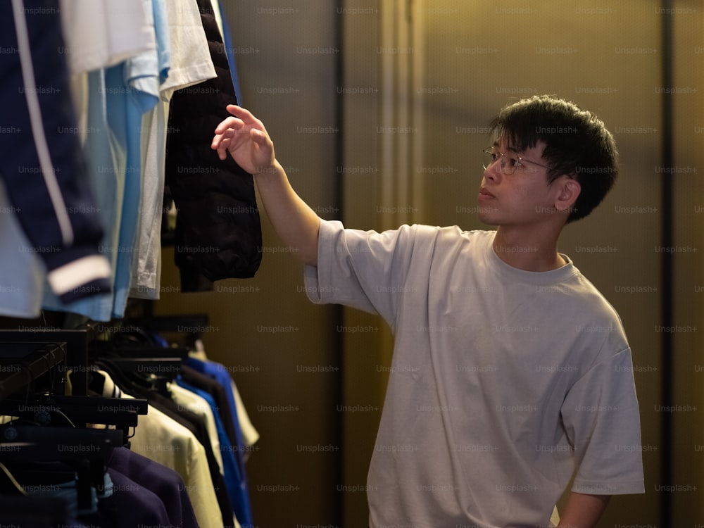a young man looking at a shirt hanging on a rack
