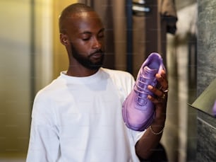 a man holding a pair of purple shoes