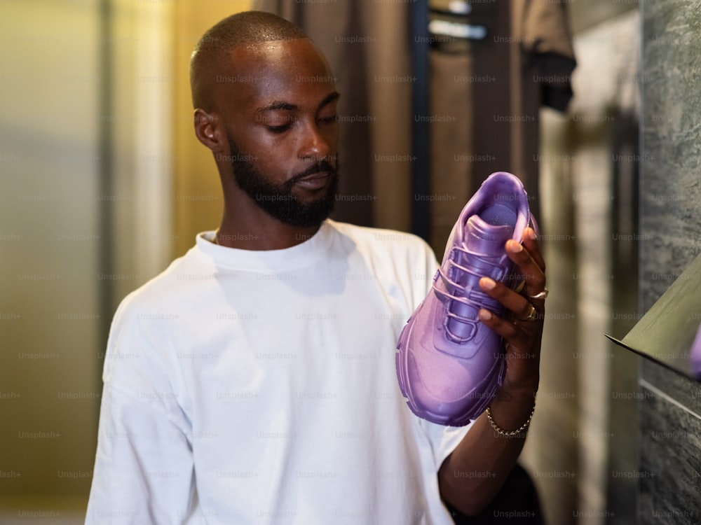 Un homme tenant une paire de chaussures violettes