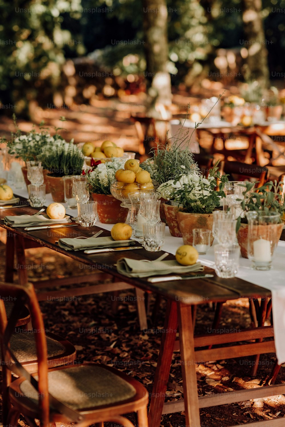 a long table is set with lemons and greenery